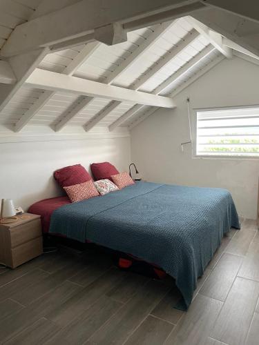 a bedroom with a blue bed with red pillows at Coconest - Duplex on the beach in Baie Nettle