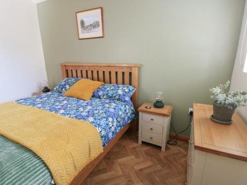 a bedroom with a bed and a night stand and a table at Trillo Lodge in Colwyn Bay