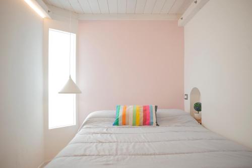 a white bedroom with a bed with a colorful pillow at Manzi 40 in Civitavecchia