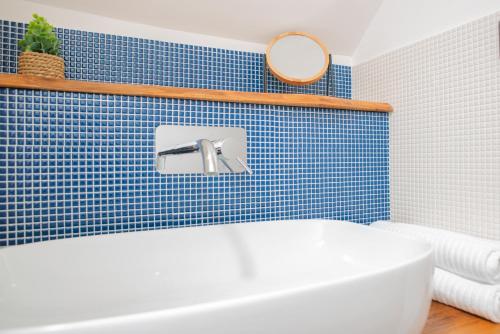 a blue tiled bathroom with a tub and a mirror at Manzi 40 in Civitavecchia
