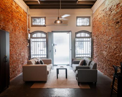 a living room with brick walls and couches at Aayu Melayu - George Town Penang in George Town
