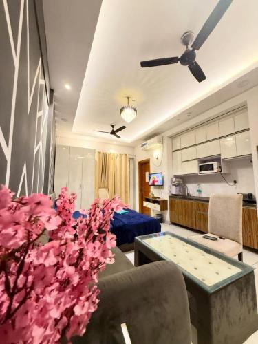 a living room with a couch and a table with flowers at Luxe Haven Stays - Luxury Studio , Premium Stay in Noida
