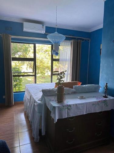 a bedroom with a bed with a table and a window at Main Stream Beach Villa in Senga