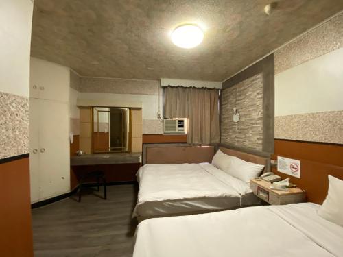 a hotel room with two beds and a bathroom at Huang Kai Hotel in Taichung