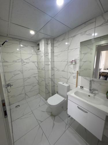 a white bathroom with a toilet and a sink at Köşk Rezidans Apart in Aksaray
