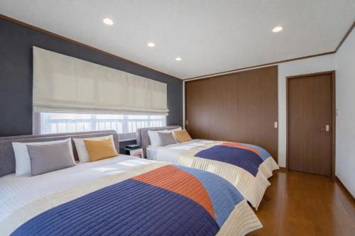 two beds in a large room with a window at Third Place Nagano in Matsumoto