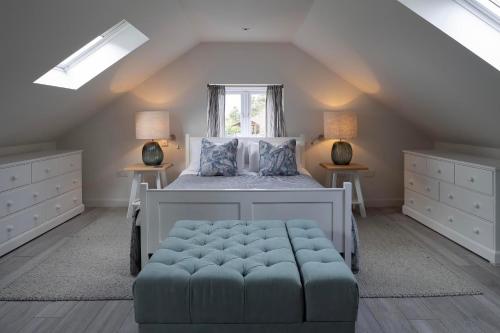 a bedroom with a bed with a blue ottoman and a window at Rose Cottage in Wadebridge