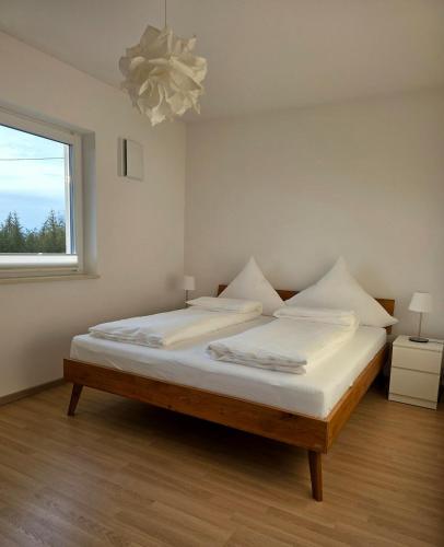 a bedroom with a bed with white sheets and a window at Apartment Ilmtalblick in Pfaffenhofen an der Ilm