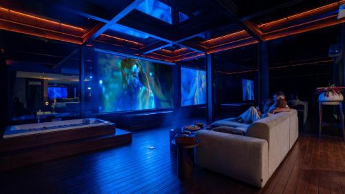 a woman sitting on a couch in a room with a large tv at Kanva Ubud in Tegalalang