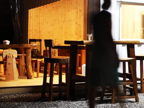 a person walking past a wooden table and chairs at Ikegami Dapo Moutain Bed and Breakfast in Chishang