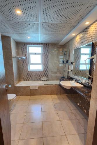 a large bathroom with two sinks and a bath tub at Tulip Al Barsha Hotel Apartment in Dubai