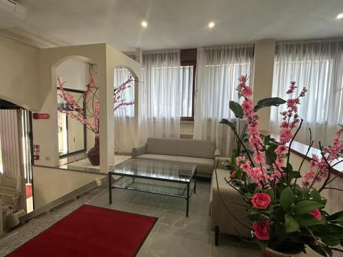 ein Wohnzimmer mit Sofa, Tisch und Blumen in der Unterkunft Hotel Nova in Varese