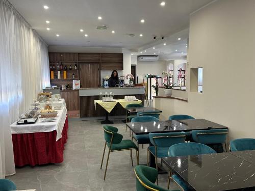 ein Restaurant mit Tischen und Stühlen und einer Frau in der Küche in der Unterkunft Hotel Nova in Varese