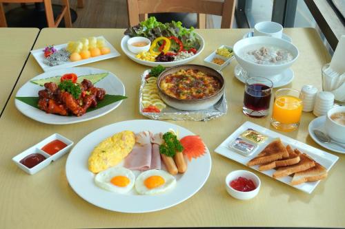a table with plates of breakfast foods and drinks at Riverine Place Hotel and Residence in Nonthaburi