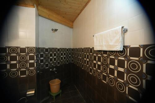 a bathroom with a shower and a towel on a wall at The Himalayan Drift Cottages in Vashisht
