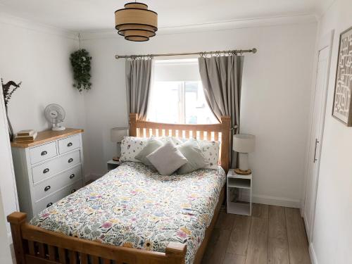 a bedroom with a bed with a dresser and a window at Carrick's Cosy Haven in Carrickfergus