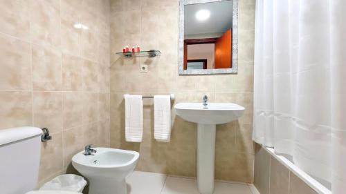 a bathroom with a sink and a toilet and a mirror at Luxmar Apartaments By MC in Benidorm