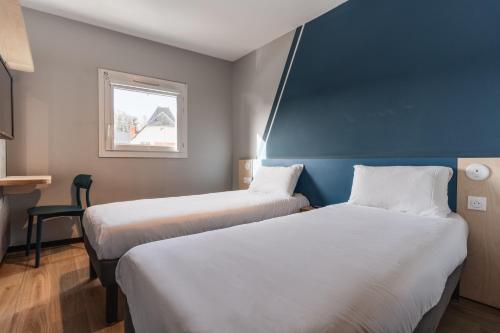 two beds in a small room with a window at Hotel Ibis Budget Fecamp in Fécamp