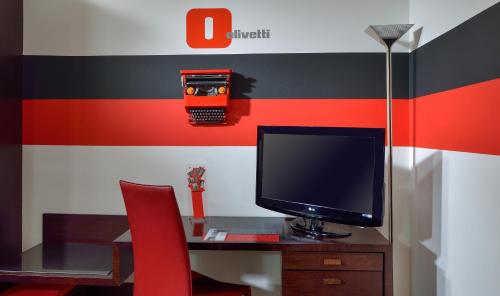 a desk with a television and a red chair at Phi Hotel Bologna in Bologna