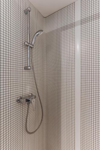 a shower in a bathroom with a tiled wall at Hotel Ibis Budget Fecamp in Fécamp