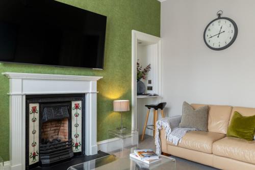 a living room with a couch and a fireplace at West Highland Apartments Milngavie - The Nevis in Milngavie