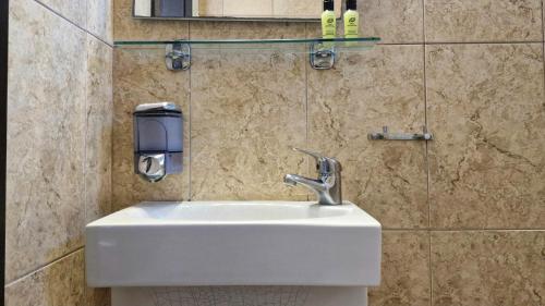 a white sink in a bathroom with a tiled wall at Plaza in Egina