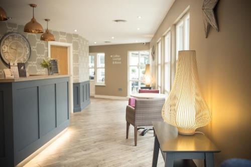 a living room with a table and a lamp at Breckland Lodge in Attleborough