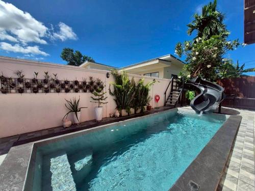 a pool with a water slide in a house at Baan Pink Pool Villa Pattaya in Ban Huai Yai