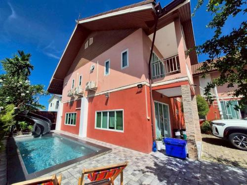a house with a swimming pool in front of it at Baan Pink Pool Villa Pattaya in Ban Huai Yai