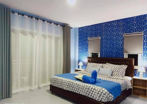 a bedroom with a bed with a blue wall at Baan Pink Pool Villa Pattaya in Ban Huai Yai