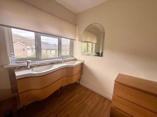 a bathroom with a large sink and a window at Spacious House Sleeps 10 -Near BikePark Wales -Central -Parking in Troed-y-rhiw