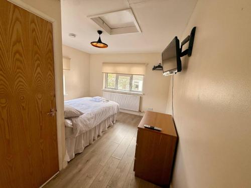 a room with a bed and a television in it at Spacious House Sleeps 10 -Near BikePark Wales -Central -Parking in Troed-y-rhiw