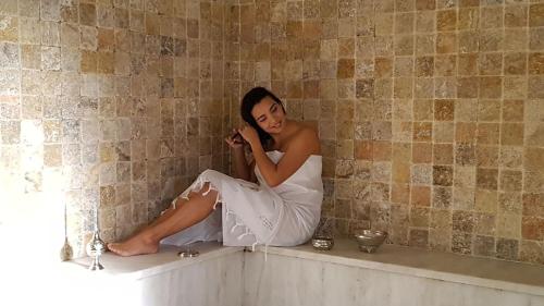 a woman sitting on a ledge talking on a cell phone at Cozy Duplex in Arles