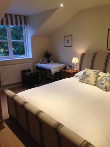 a bedroom with a large bed with a table and a window at Mill Cottage in Malpas