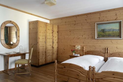 a bedroom with a wooden wall with a bed and a table at Hotel Bad Serneus in Klosters