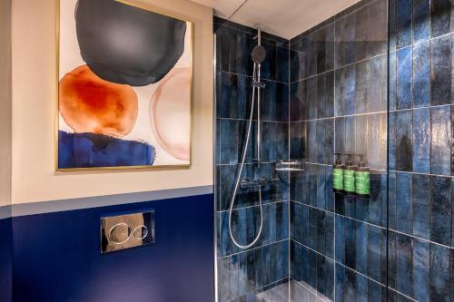 a bathroom with a shower with blue tiles at voco Gent by IHG in Ghent