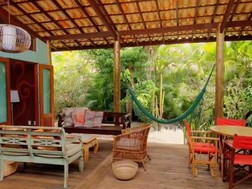 a porch with a hammock and a table and chairs at Casa Morada dos Pássaros - 3 suítes in Imbassai