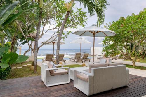 a deck with chairs and umbrellas on the beach at Villa Oceana, Candidasa in Candidasa