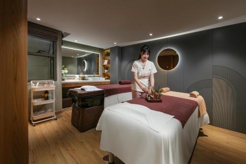 a woman standing in a room with two beds at Hong Ngoc Cochinchine Boutique Hotel & Spa in Hanoi