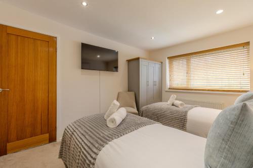 a bedroom with two beds and a tv and a window at Newhaven in Telford