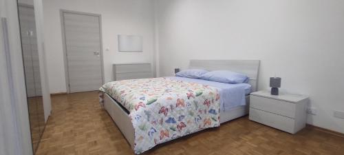 a white bedroom with a bed and a night stand at Alloggio Tobia in Biella