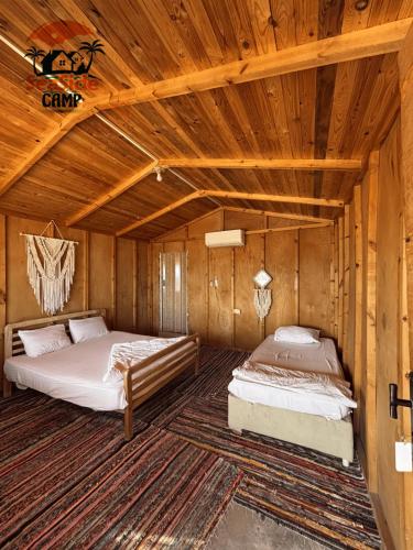 two beds in a room with wooden walls at The Sea side camp nuweiba in Nuweiba