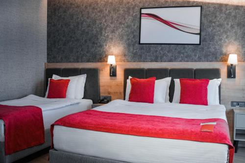 two beds in a hotel room with red pillows at Ramada by Wyndham Dalaman in Dalaman