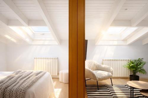 a bedroom with a bed and a chair at Corazón de la Ciudad by apartamentoscatedralcamino in Burgos