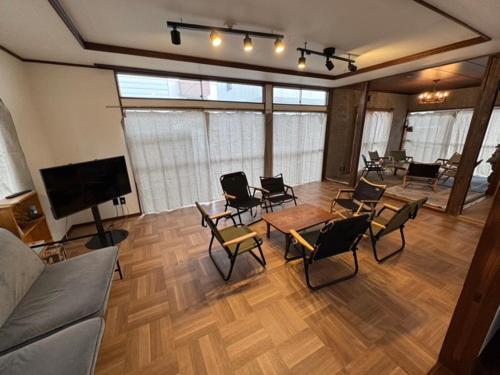 a living room with chairs and tables and a flat screen tv at 『貸切、BBQ 可、送迎あり』Nonbiri Slowly Plant in Oiso