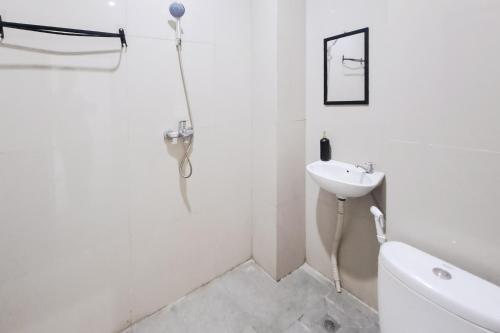 a white bathroom with a sink and a shower at SANS Stay Raja Soeta Hostel Lampung in Hajimana