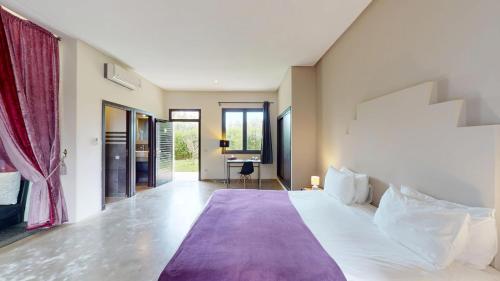 a bedroom with a large bed with a purple blanket at Villa Agapanthe in Fez