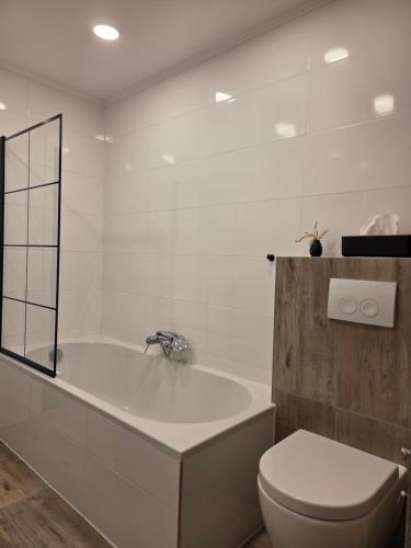 a white bathroom with a tub and a toilet at Ferienwohnung Lux in Ortenberg
