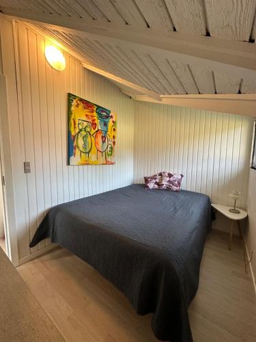 a bedroom with a bed and a painting on the wall at Glamping Cabin Wilderness bathing and relaxation in Silkeborg