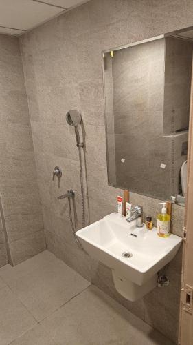 a bathroom with a sink and a shower with a mirror at Romaer's Room in Greater Noida